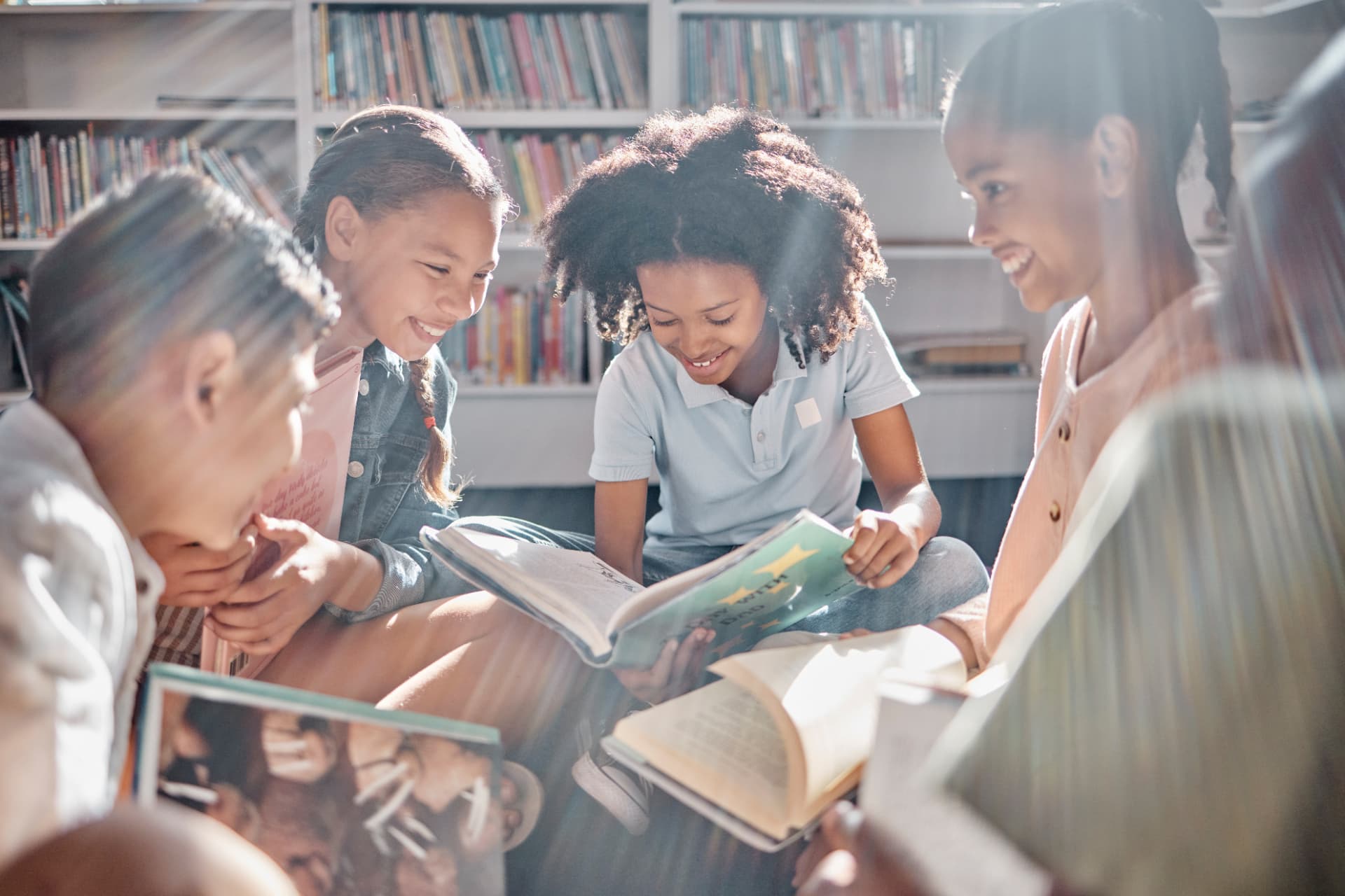A mentor reading a picture book with a diverse group of smiling elementary students